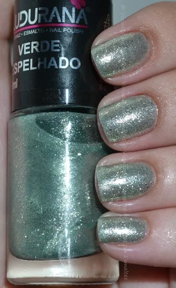 Unhas com esmalte Ludurana Verde Espelhado fotografado com flash, destacando as partículas de prata